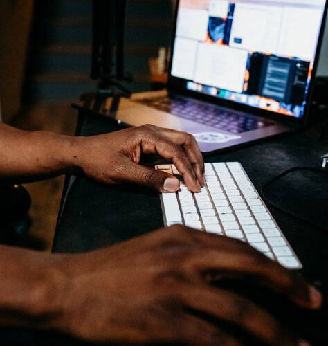 Homme pianotant sur un clavier avec un ordinateur portable ouvert à côté