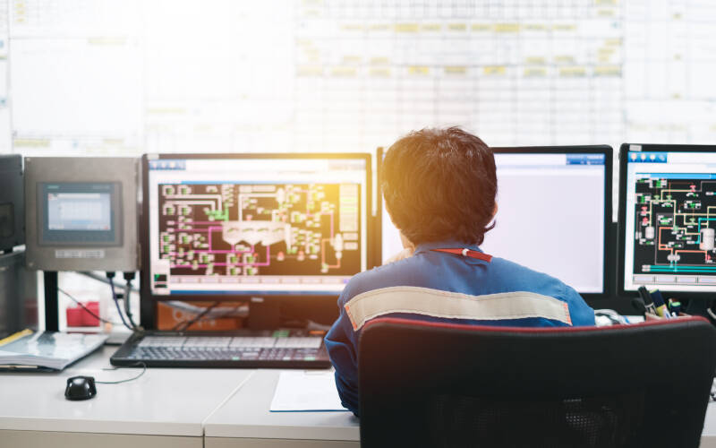 Homme devant plusieurs écrans sur différents logiciels de développement
