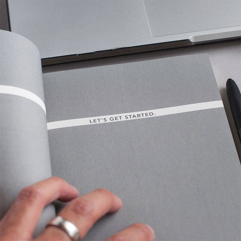 Main féminine posée sur un carnet où est écrit lets get started