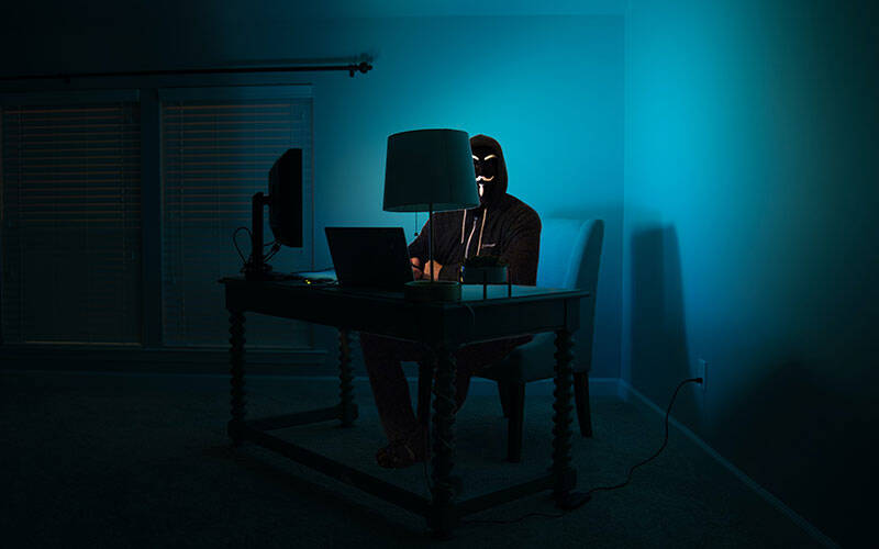 Photo caricatural d'un hacker dans une pièce sombre