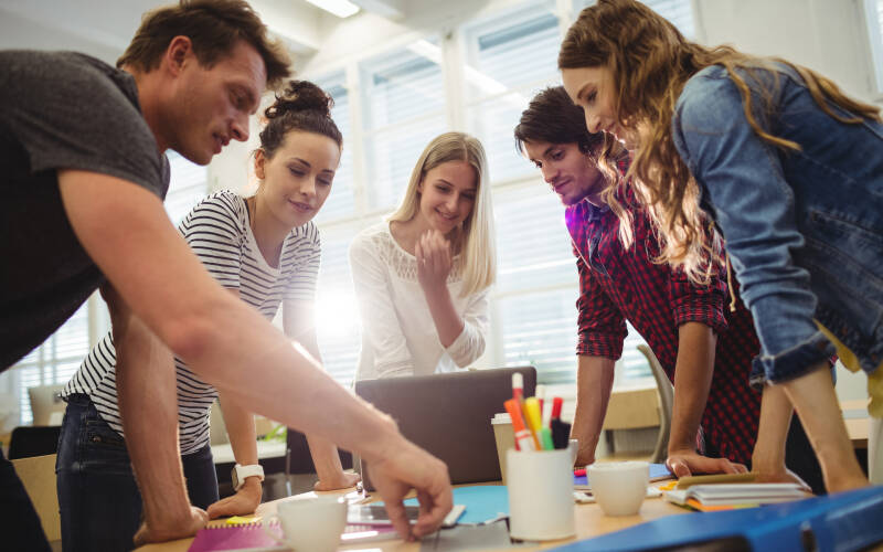 Groupe de personnes qui échangent autour d'une table en pointant des informations disposées dessus