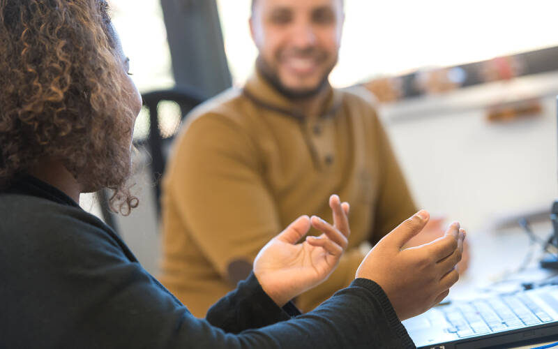 2 personnes échangent avec le sourire devant leur bureau
