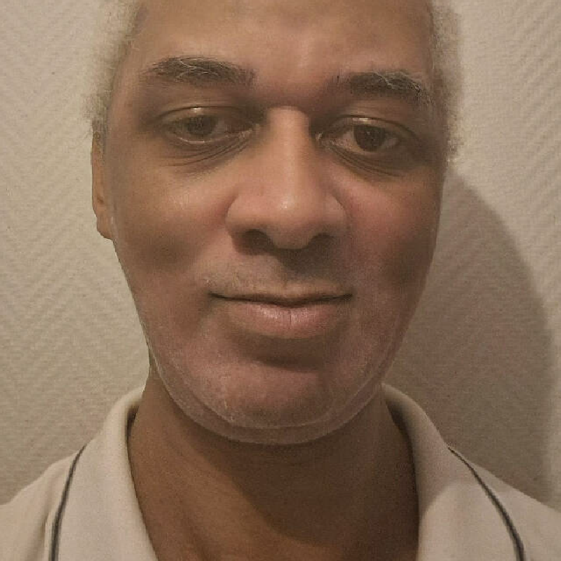Un homme de face devant un fond neutre