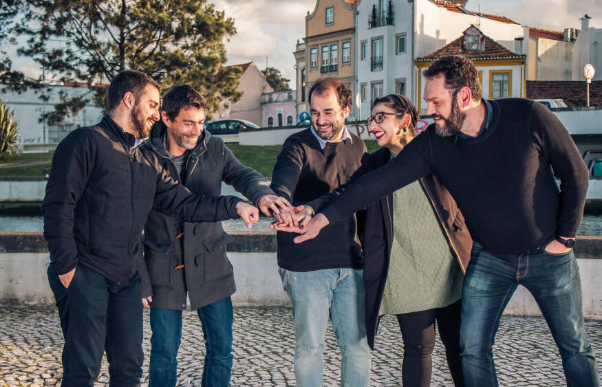 Des hommes et des femmes souriants faisant un début de cri de guerre avec leurs mains