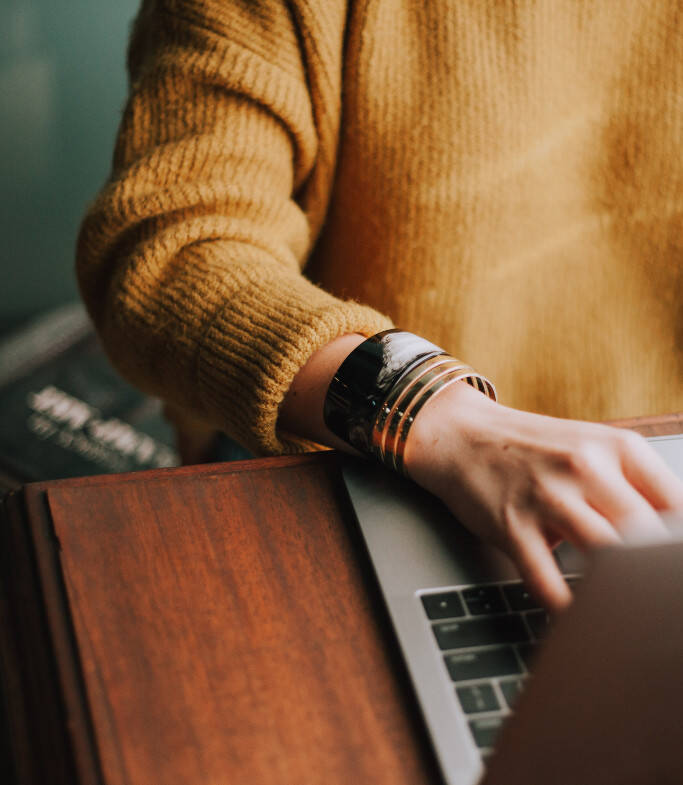 Focus sur le bras droit d'une femme en train de taper sur le clavier d'un ordinateur