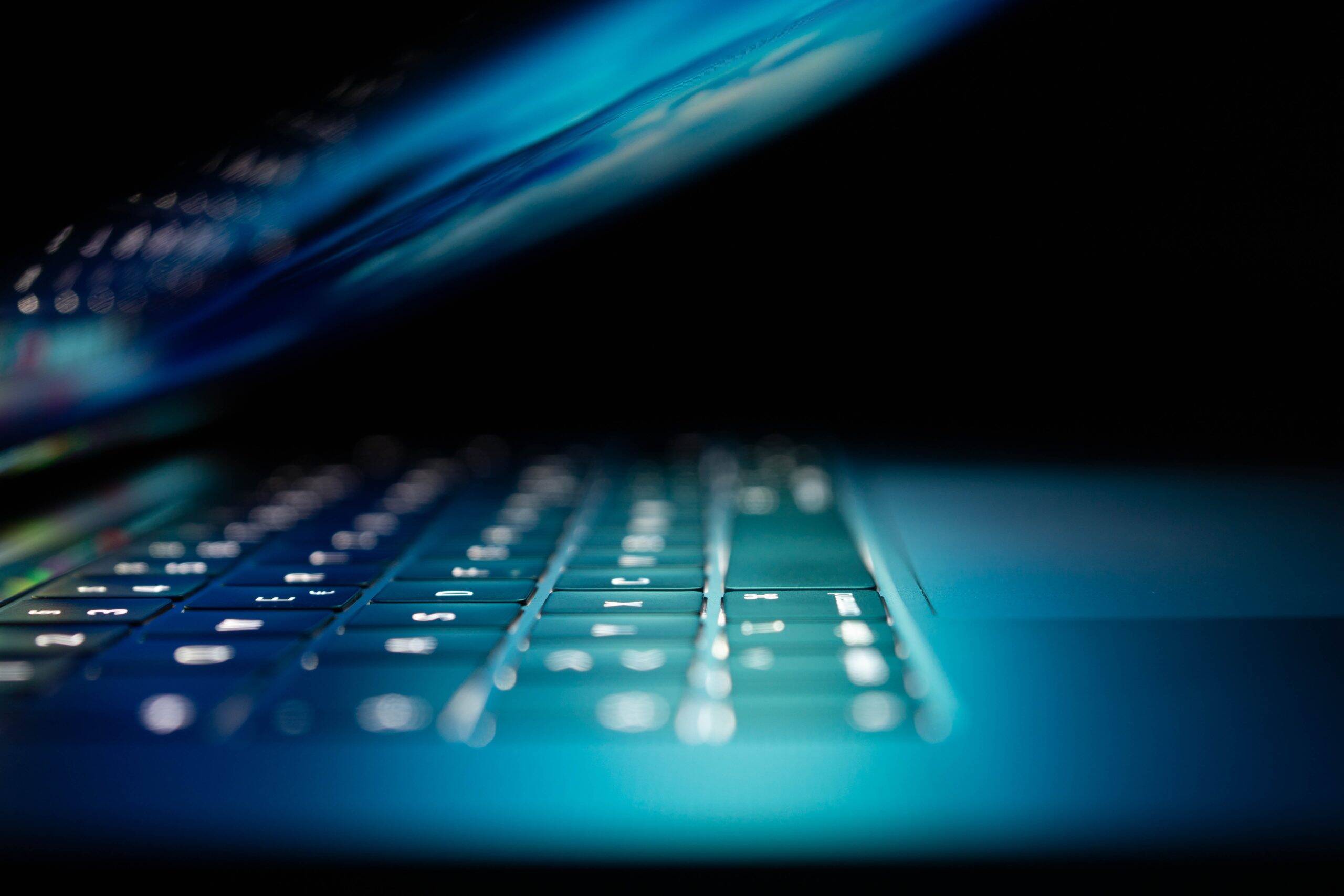 Ecran entrouvert laissant entrevoir une lumière bleutée reflétée sur le clavier