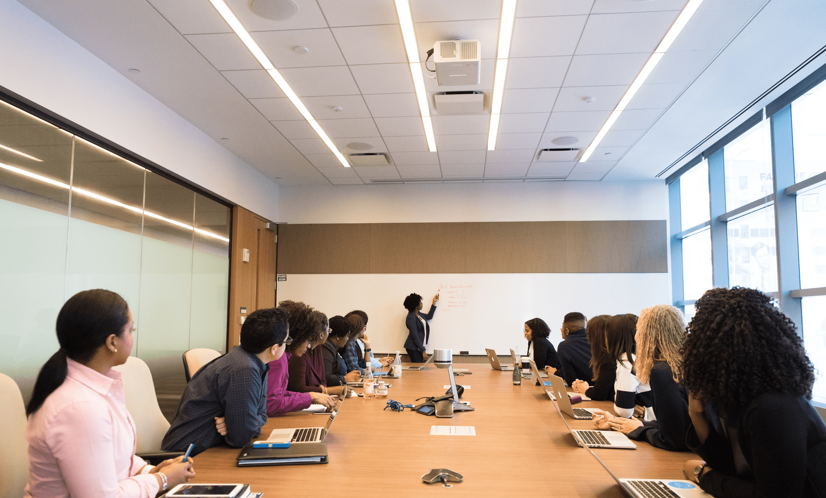 les personnes présentes à la table de conférence regardent la femme qui parle