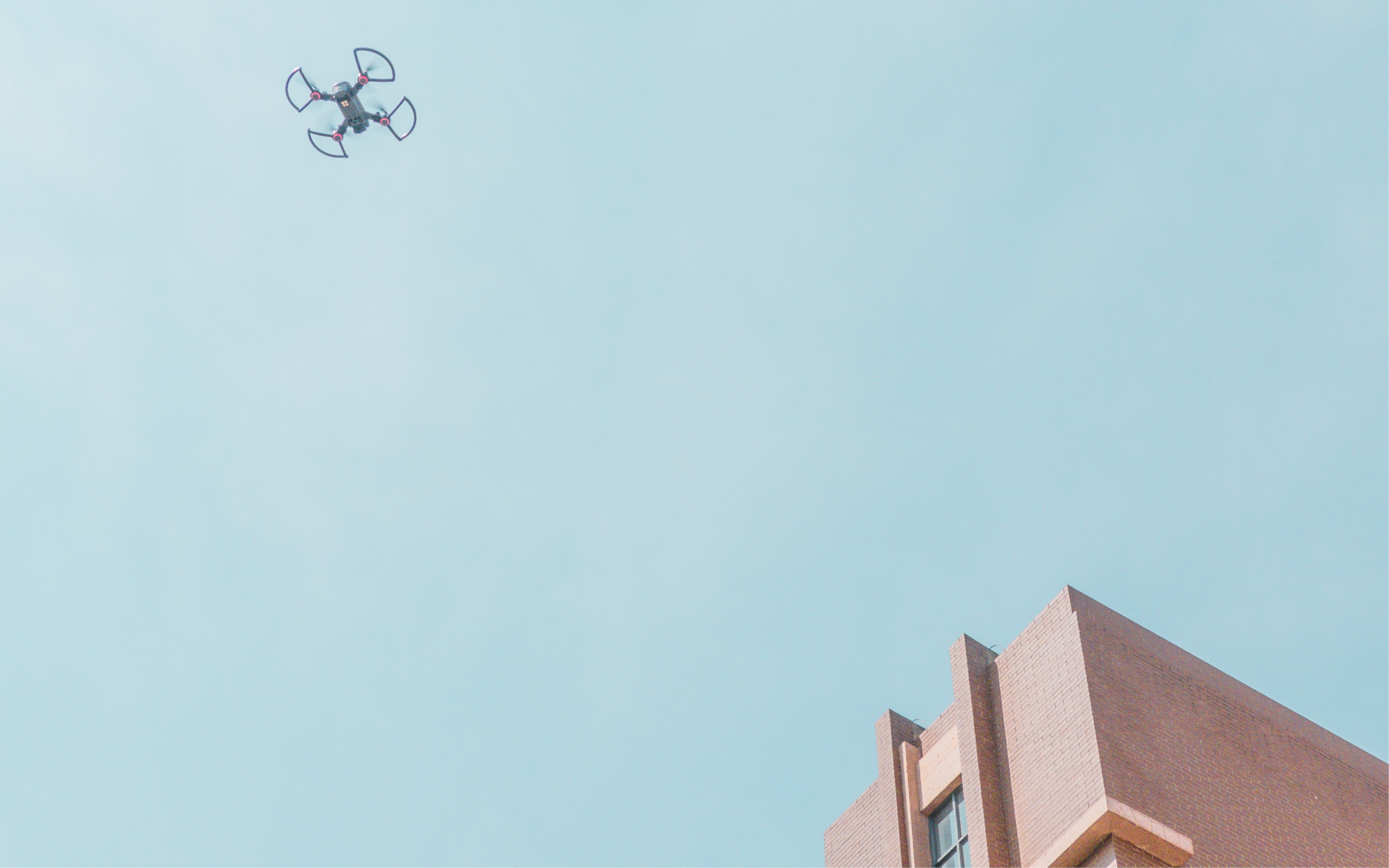 Un drone volant au dessus d'un bâtiment avec un ciel bleu en arrière-plan