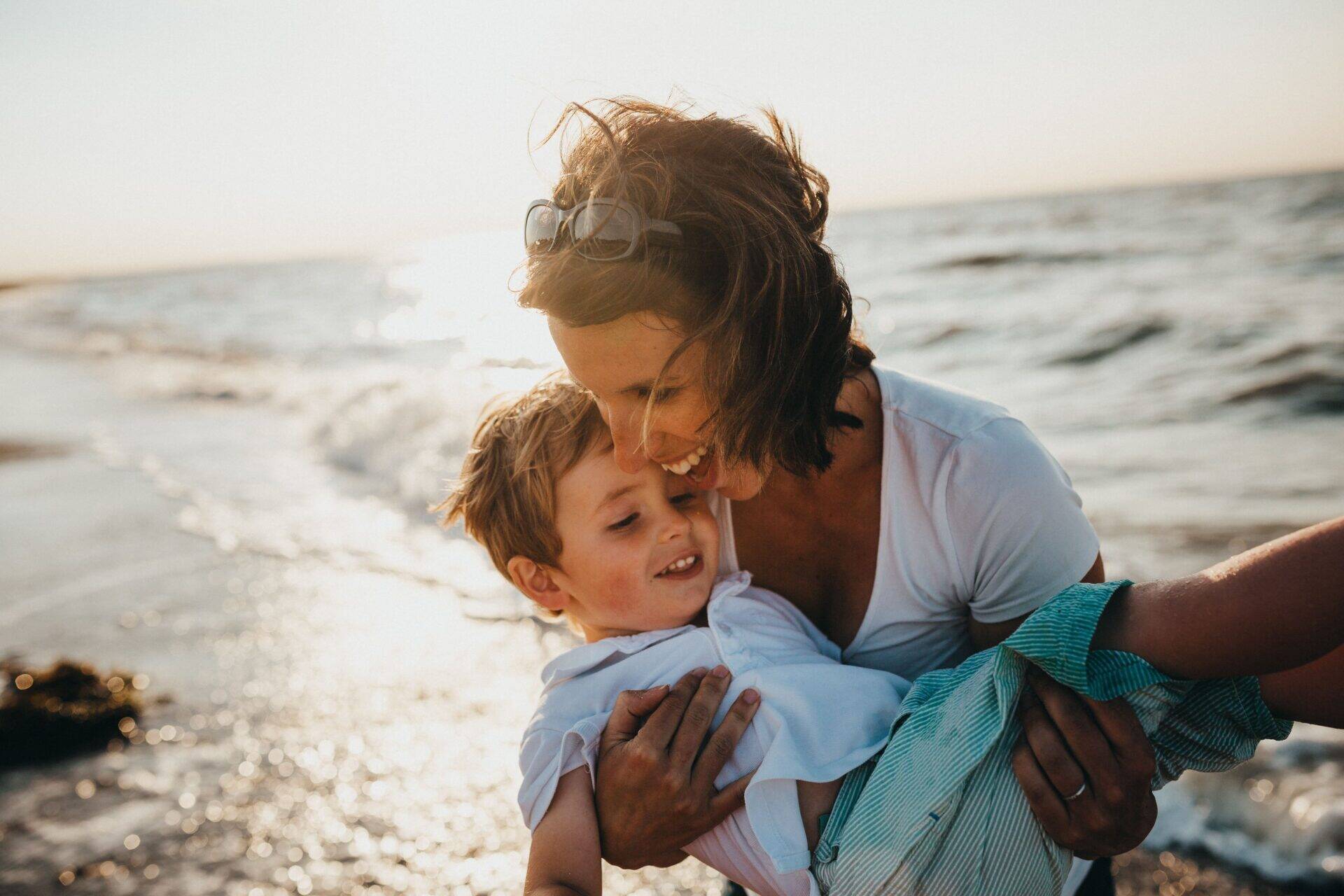 femme portant son enfant au bord de mer vie