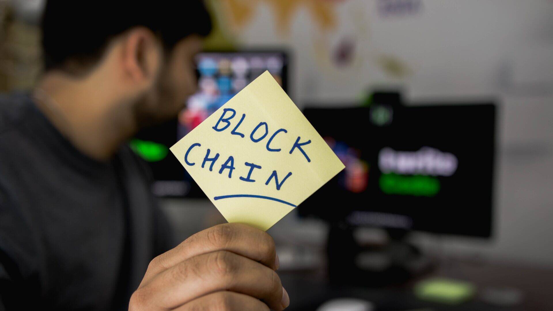 homme montrant un postit avec écrit blockchain banque