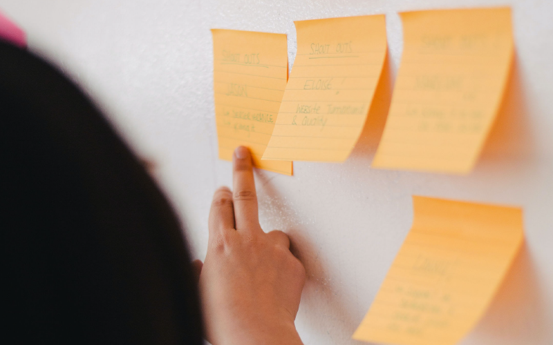 Une femme utilisant des post-it sur un tableau blanc