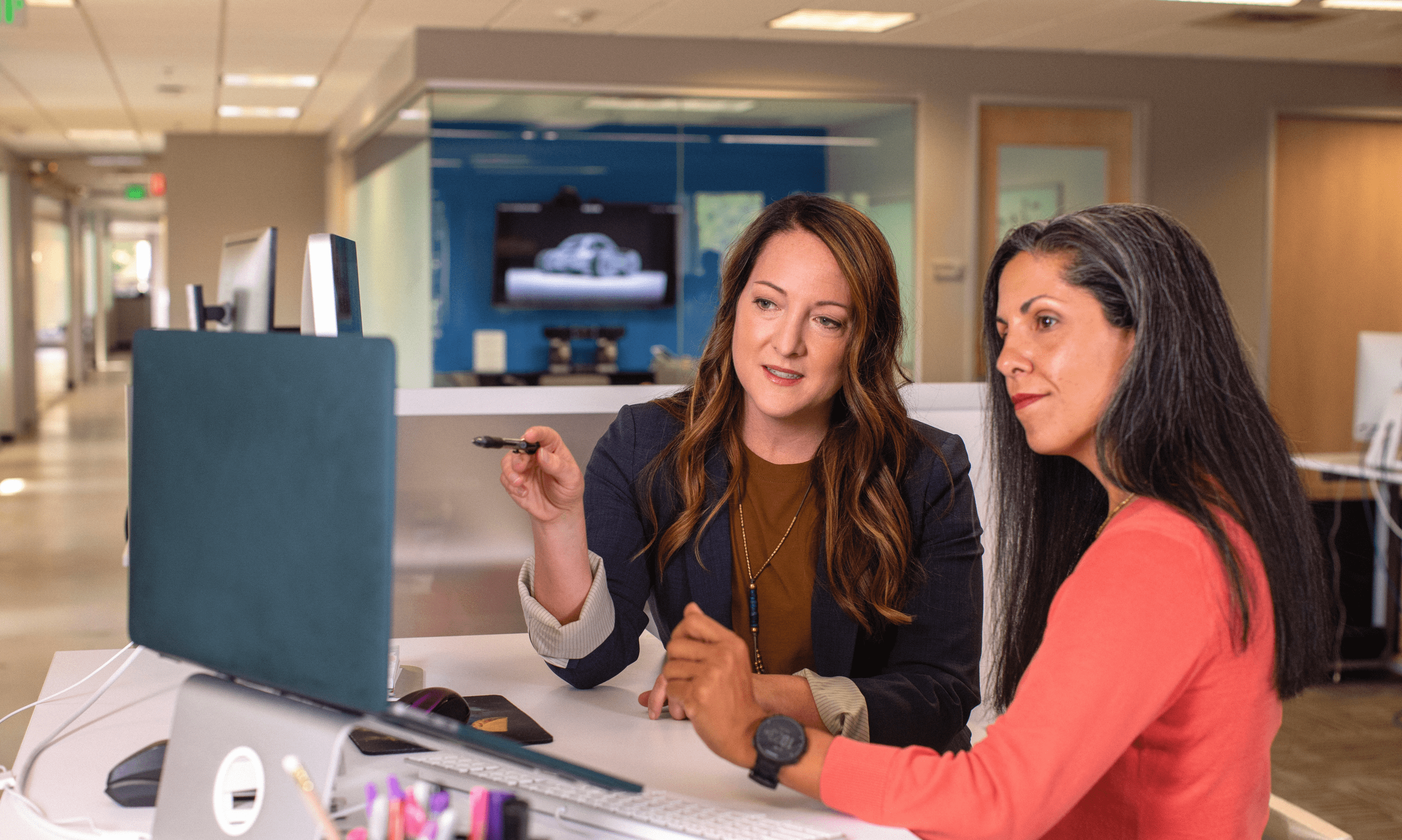 Deux femmes assises à une table regardant un écran d’ordinateur