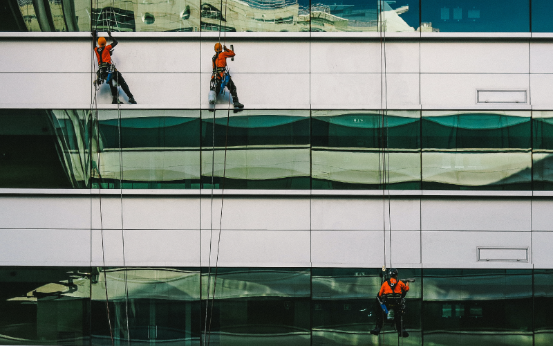 3 hommes lavant une façade d'immeuble