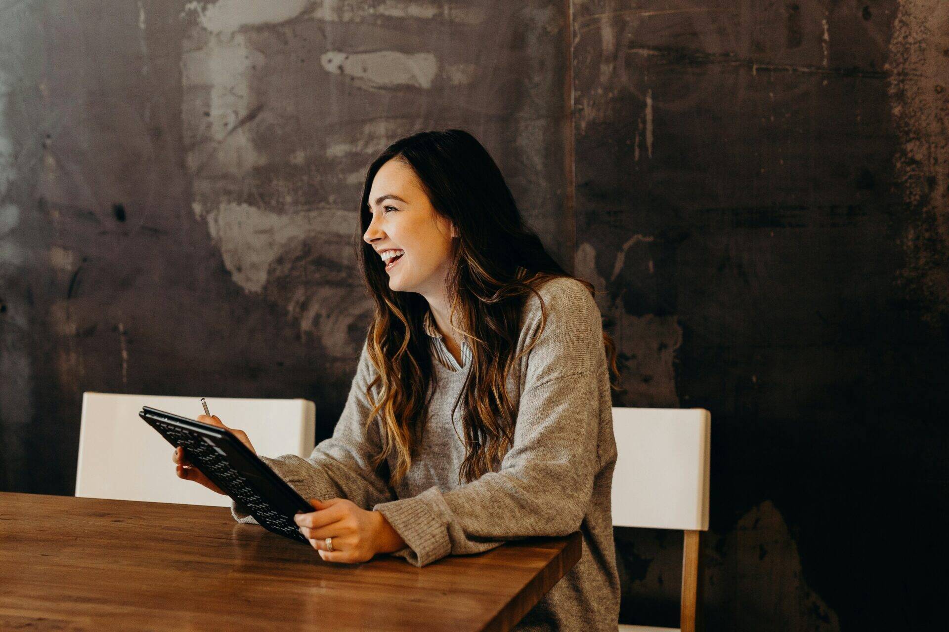 Femme souriant à un bureau avec une tablette dans la main